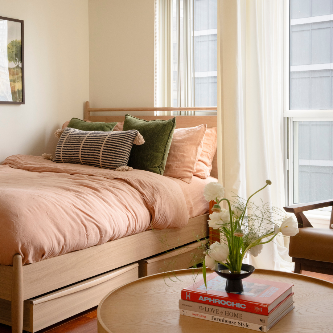 Bedroom with pink bedding and a round table with books and flowers
